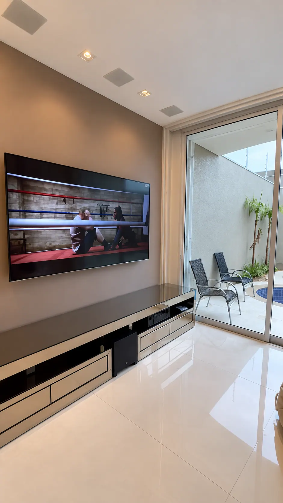 Sala com TV, iluminação linear e caixas de som no teto