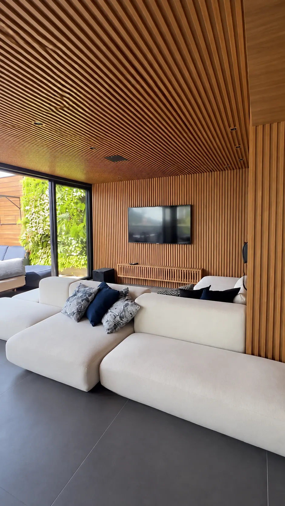 Sala com TV e áudio integrado ao teto de madeira